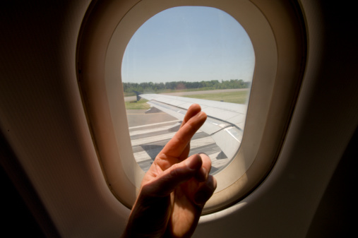 Male passenger crossing fingers while plane takes off